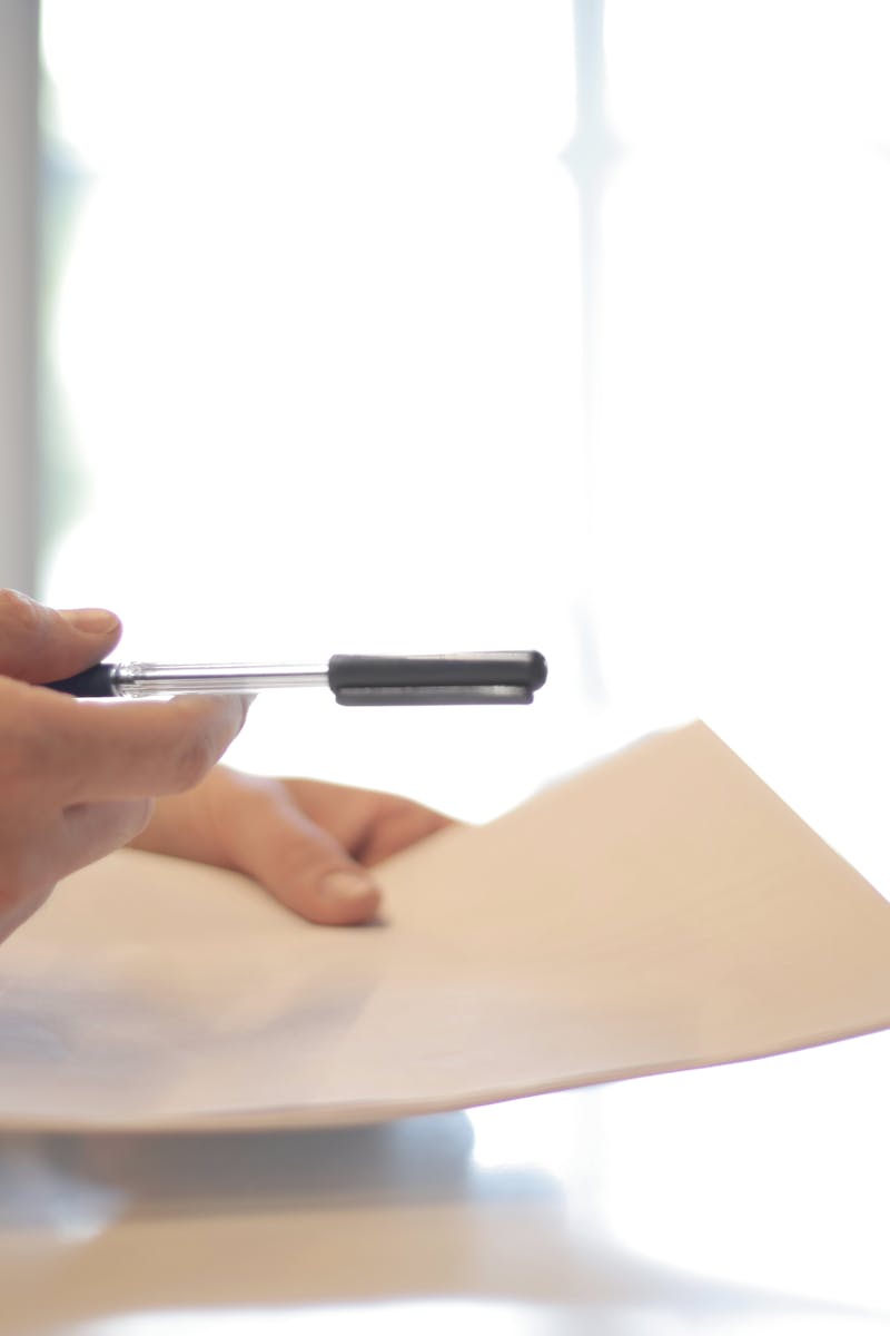 Close-up of a contract signing with hands over documents. Professional business interaction.